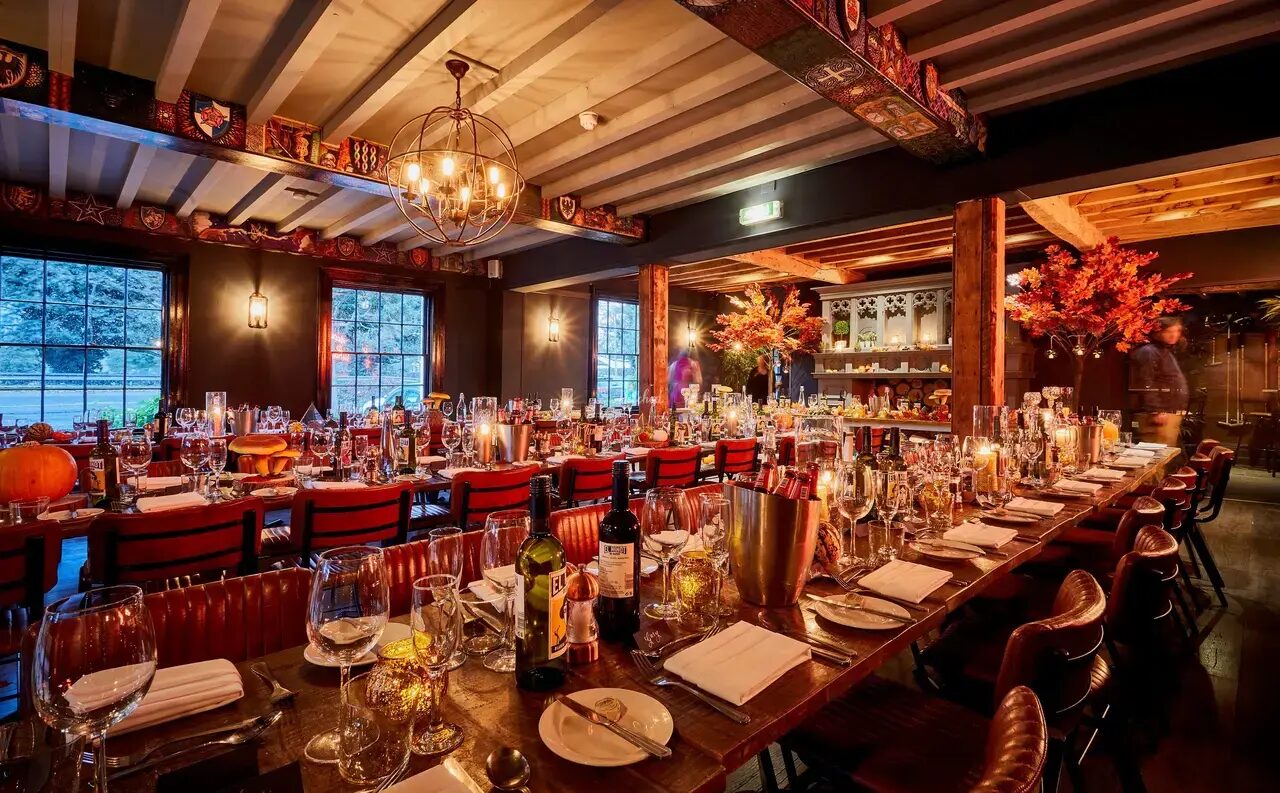 A long table set for dinner in the restaurant, beneath exposed beams and lantern light