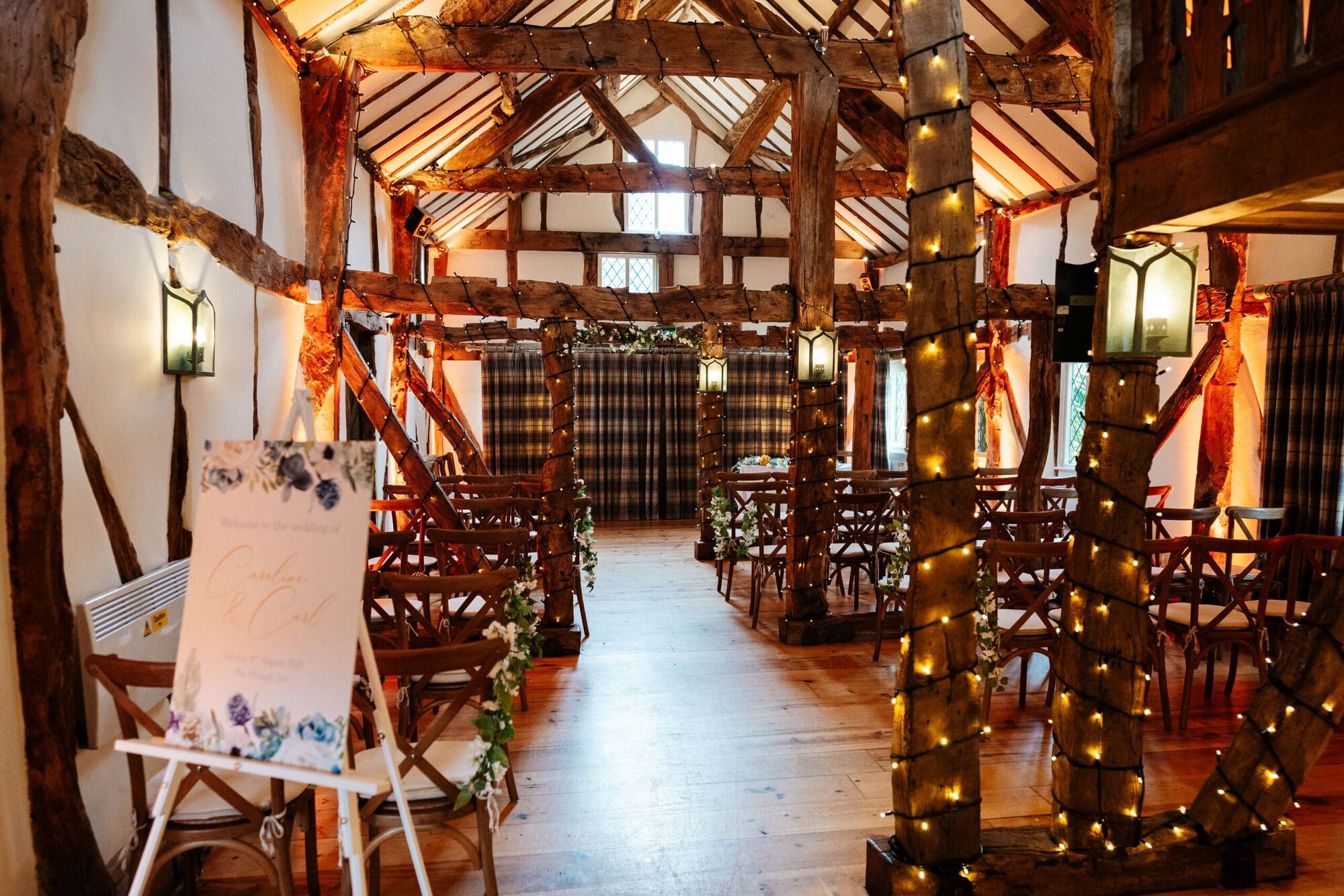 The Plough’s timber-beamed barn set for a wedding ceremony, with fairy lights wound around the posts